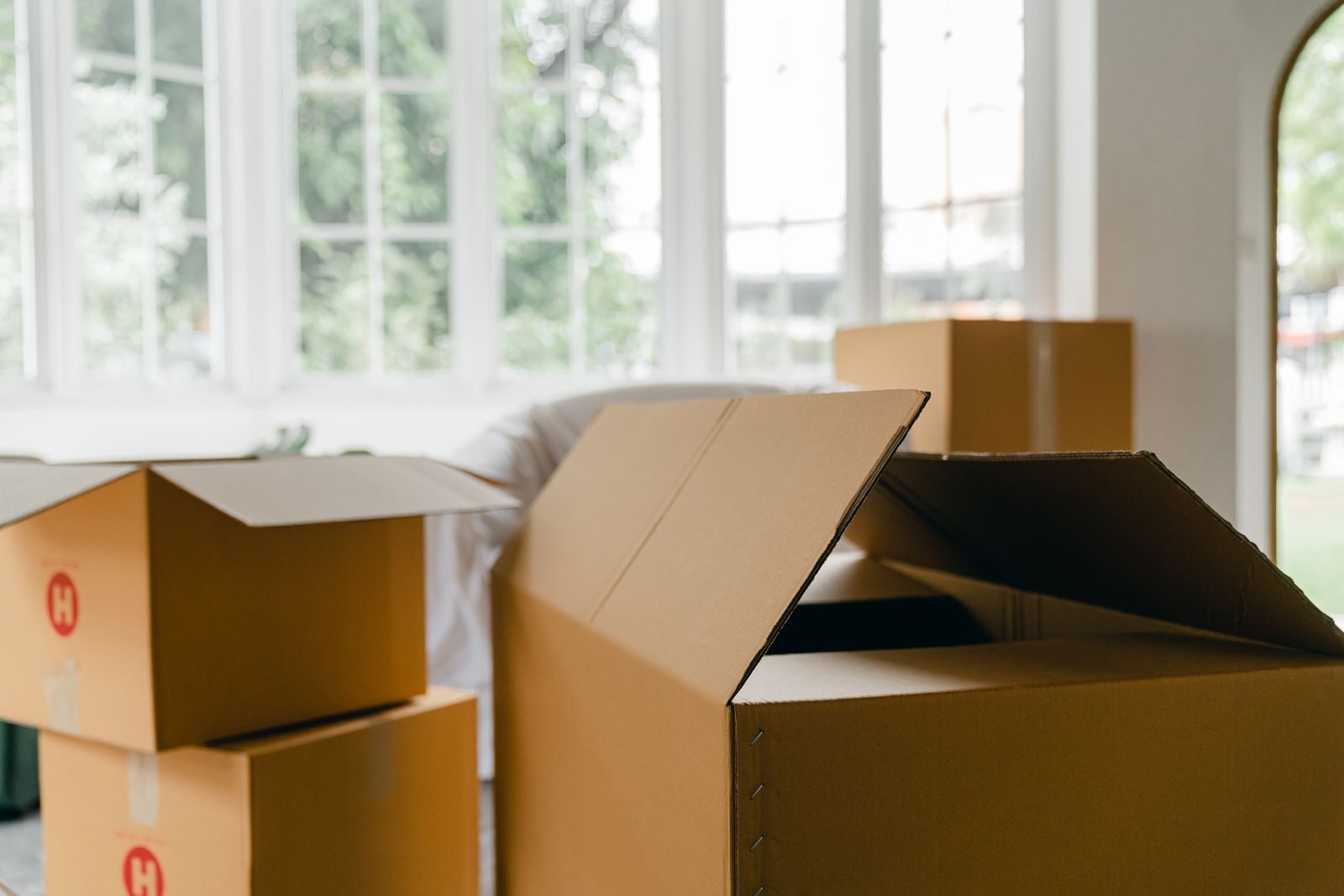 A stack of cardboard moving boxes in a bright, sunlit room mid-move