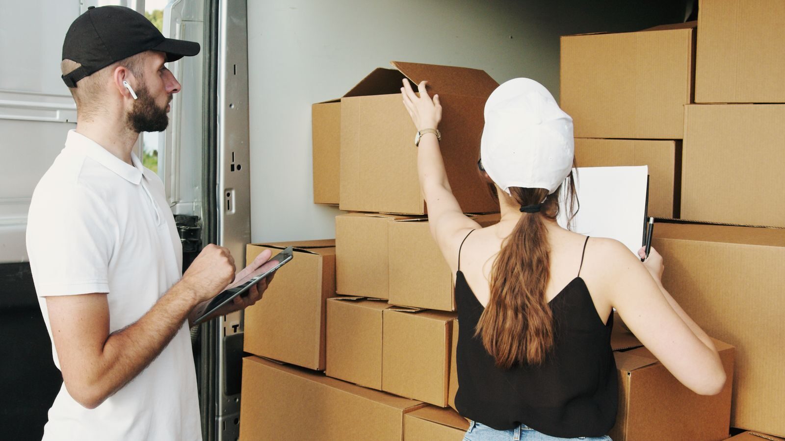 Two removalists loading cardboard boxes into a moving van