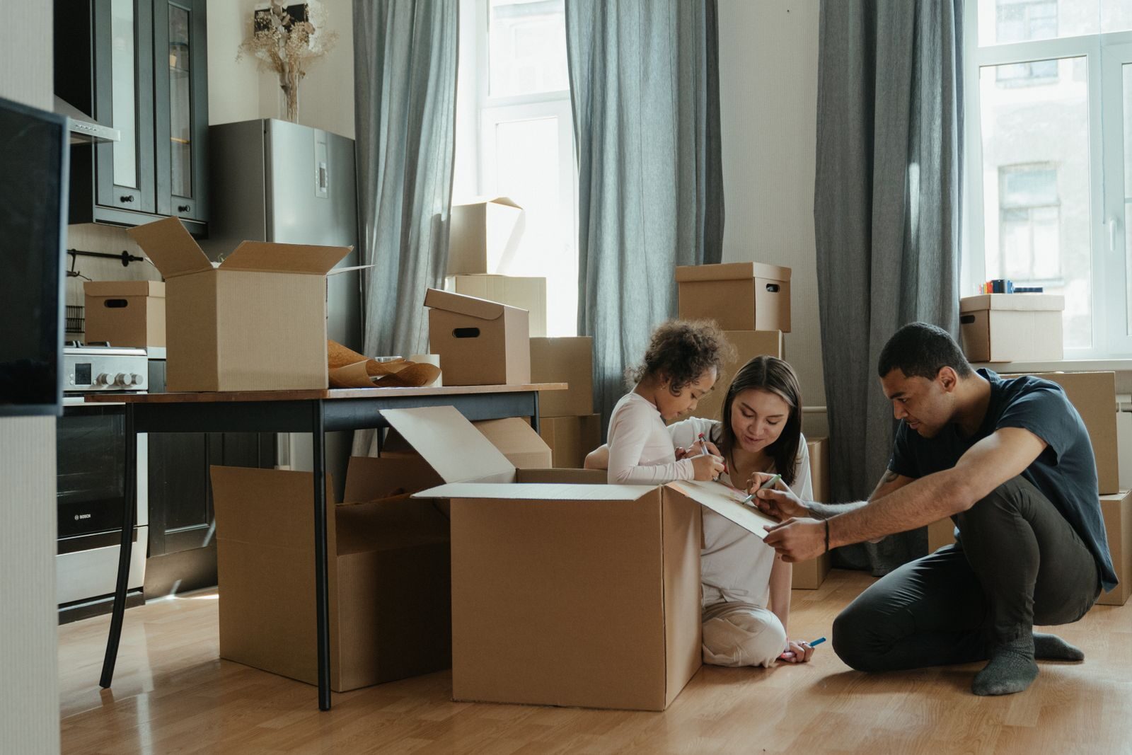 A family packing cardboard boxes together in a partly-packed home